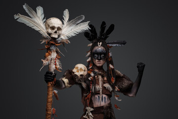 Shot of dark female sorcerer dressed in ancient aboriginal clothes holding staff.