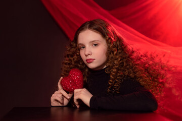 girl with a red heart in her hands on a red background
