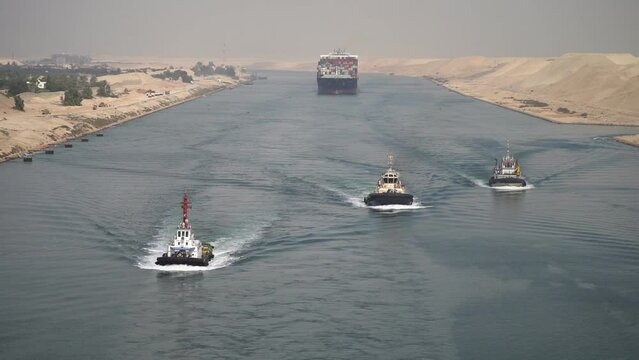 Huge cargo ships with pilot boats navigate by Suez Canal, Egypt. Concept of transportation and logistics 