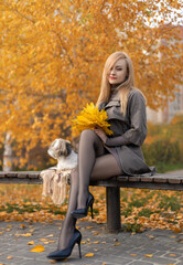 Beautiful woman with perfect legs sitting in the autumn park with a cute Shih-Tzu dog