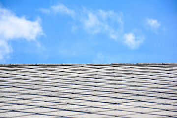Asbestos slate roof with blue cloudy sky.