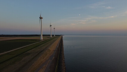 Obraz premium Aerial photo of wind turbines near the sea during sunset