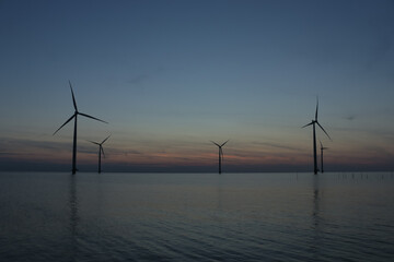 Obraz premium Aerial photo of wind turbines in the sea during sunset