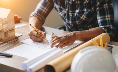 business man hand working and laptop with on on architectural project at construction site at desk in office