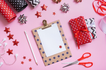 Blank note and christmas presents with wrapping paper flat lay on pink background