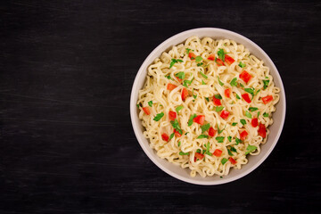 Instant noodles in bowl on black background