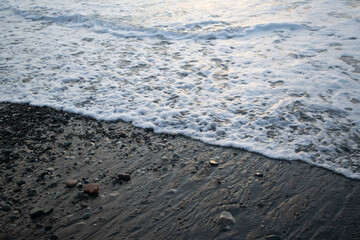 Fototapeta na wymiar Sea foam from the waves on the shore