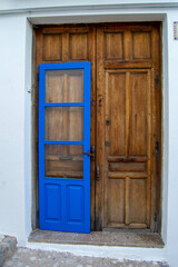 Gran puerta de madera marrón de una casa del pequeño pueblo de Altea en Alicante con otra puerta más pequeña delante pintada de azul.