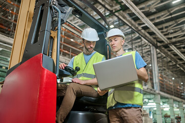 Men in protective helmets working in a storage area