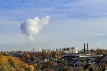 intense cloud of smoke from the plant's pipes against the blue sky, environmental pollution