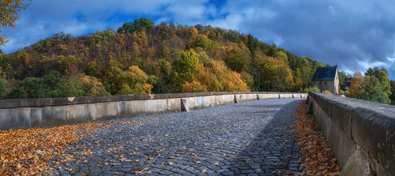 Auf der historischen Werrabr&uuml;cke in Creuzburg, Th&uuml;ringen mit der Liboriuskapelle im Hintergrund, im Herbst