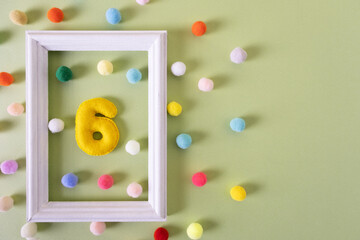 The number Six for a birthday in a white frame with colored balls. Festive concert, party, anniversary