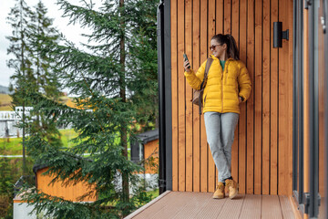 Young female in yellow down jacket with leather retro tourism backpack have a rest in nature...