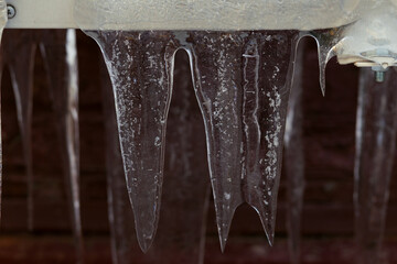 Big flat icicles hanging from an air conditioner.