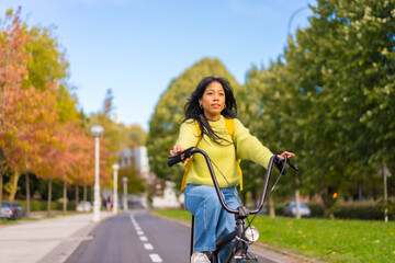 Fototapeta premium Young asian female student cycling on her way to university campus, healthy life, eco friendly