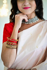 Indian woman in Saree and Jewellery. Red and White Saree. Bracelets. Traditional Glass Bracelets. Traditional Indian Silver neckless and earrings. White Background
