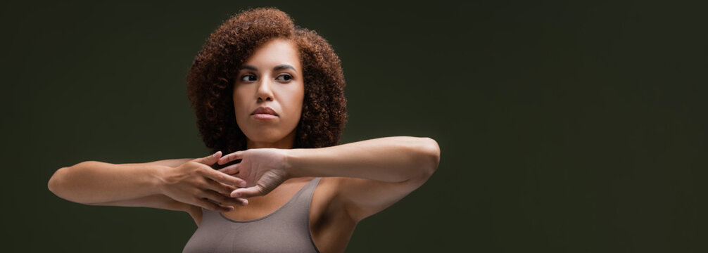 Curly African American Woman In Top Touching Hands Isolated On Dark Green, Banner.