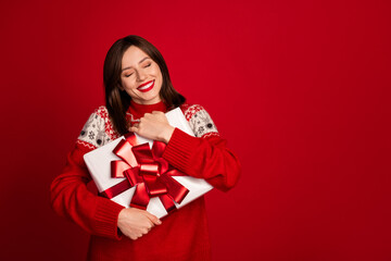 Fototapeta premium Portrait of thankful funny positive woman bob hairdo dressed red sweater hug present box eyes closed isolated on red color background
