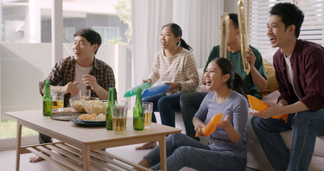 Group of young adult friend man and woman asia people sit at sofa couch joy chanting party fun game FIFA world cup live TV at home eat snack bowl drink beer bottle glass jump mad happy win exult face.