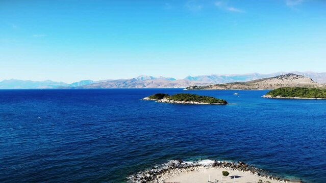 Flying over blue scape seaside ionic seaside with islands, touristic holidays aerial shot, blue water, sunny day, albania ksamil