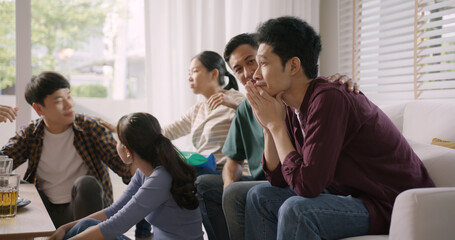 Obraz premium Group of asia people young adult friend man and woman scream shout excited sit at home sofa couch watch FIFA world cup game live on TV feeling upset disappointed sad anger in loss racing result.