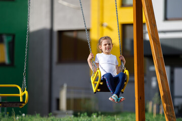 Happy child sitting on a seesaw at playground on a sunny summer day