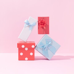 Christmas gifts creative composition. Red and blue present boxes against pastel pink background. Happy Christmas or New Year concept. Minimal holidays celebration aesthetic.