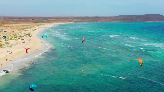 Kite surfers training in Sal, Cape Verde. 4K aerial drone view of coastline. Wavy ocean. Turquoise colorful ocean. Wide angle view.