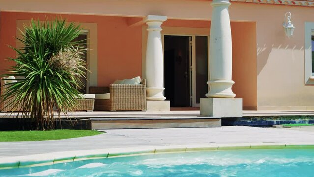 White Door Of A Villa That Opens Alone, Columns, Small Palm Tree And Swimming Pool In The Foreground