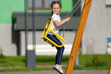 Happy child sitting on a seesaw at playground on a sunny summer day
