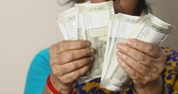 Close up of female hands counting a 500 rupees notes of Indian money by hand, a woman counts cash. A woman counting new Indian money. Indian Rupee, Home Finance concept. Selective focus