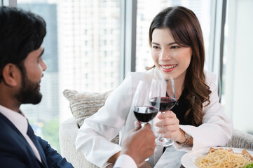 Asia businesswoman cheers with husband at restaurant and city out of window background	