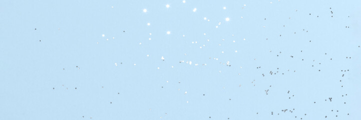 Sparkling silver glitter on blue background banner texture. Abstract holiday blurred lights header. Wide screen wallpaper. Panoramic web banner with copy space for design