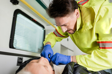 Paramedic in uniform and latex gloves taking off clothes from patient during first aid.