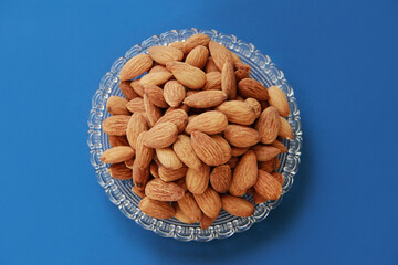 grains of natural brown almonds in a transparent glass plate