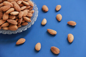 grains of natural brown almonds in a transparent glass plate