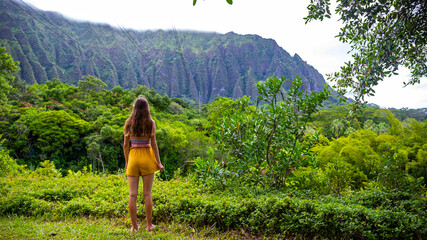 beautiful girl walks through Ho'omaluhia Botanical Garden admiring the mighty mountains on oahu,...