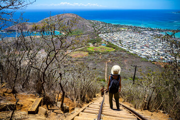 backpacker girl in hat hiking on steps of famous koko crater railway trailhead, oahu, hawaii,...