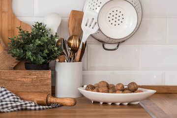 Fototapeta na wymiar Dishes and cutlery on the kitchen wooden countertop, ready to cook. White modern kitchen in Scandinavian style, kitchen details.