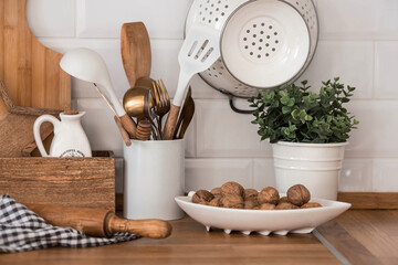 Dishes and cutlery on the kitchen wooden countertop, ready to cook. White modern kitchen in...