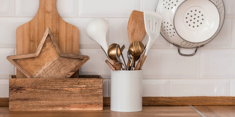 Dishes and cutlery on the kitchen wooden countertop, ready to cook. White modern kitchen in...
