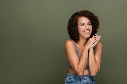 Cheerful african american woman in top looking away isolated on green.