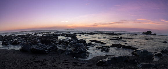 Panorama of rocks along the Pacific coast at sunset.