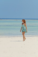 Fototapeta premium Young pretty woman on the tropical sandy beach with turquoise water sea background, Zanzibar 