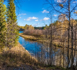 Autumn landscape with river, trees, grass and blue sky