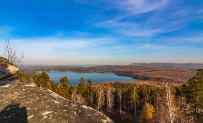 Autumn landscape from the top of a mountain with a lake, trees, mountains and sky