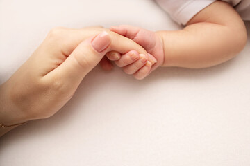 Close-up little hand of child and palm of mother and father. The newborn baby has a firm grip on the parent's finger after birth. A newborn holds on to mom's, dad's finger. 
