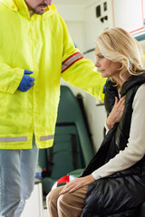 Paramedic in uniform calming mature woman in emergency vehicle.