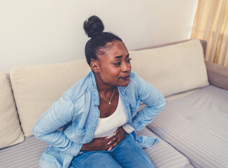 Cropped shot of an attractive young woman sitting on her bed and suffering from period pains at home. Woman with menstrual pain.