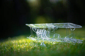 Transparent plane made of ABS plastic on green grass.Laser cutting.Modeling of aircraft models. A...